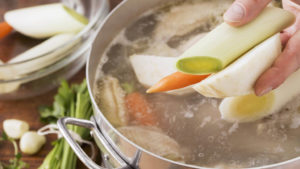 Vegetables being added to a soup chicken